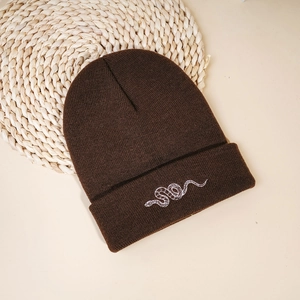 Close-up of dark brown ribbed knit beanie featuring detailed white snake embroidery