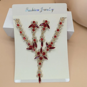 Close-up of elegant V-shaped necklace and drop earrings with red crystals on a gold base