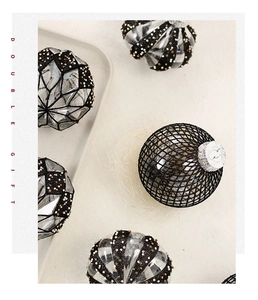 Detail of Christmas balls with black mesh, gold sequins and geometric facets on a tray