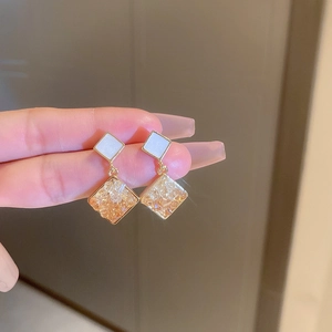 Detail of square crystal drop earrings with gold metallic edges and glittery stone inlay
