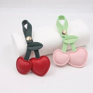 Detail of red and pink leather cherry charms with green leaves and metal clasp
