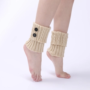 Close-up of beige cable-knit leg warmers with cuff design and two decorative black buttons