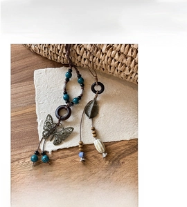Detail of bohemian ceramic butterfly necklaces with adjustable wax rope and leaf charms