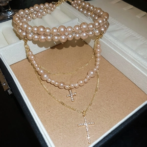 Detail of layered pearl necklaces with crystal cross pendants in vintage luxury style