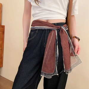 Detail of silk-like neckerchief with geometric patterns used as a fashion waist belt on jeans