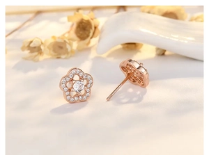 Macro shot of rose gold flower earrings with pavé cubic zirconia petals and silver pins