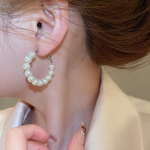 Close-up of geometric circular pearl hoop earrings with silver needles on a model