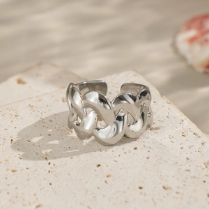 Detailed close-up of a silver cuban link ring on a textured beige stone background