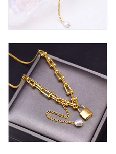 Detail of gold U-shaped link necklace with LOVE engraved lock pendant and white pearl