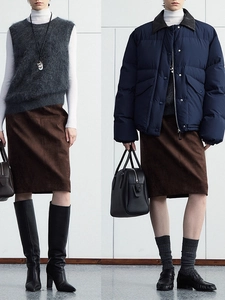 Women's autumn outfit featuring navy down jacket, grey vest, and brown suede midi skirt