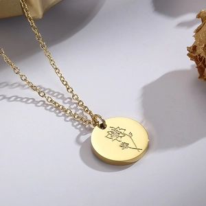 Gros plan d'un collier doré en acier inoxydable avec pendentif fleuri sur un fond minimaliste