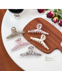 Detailed top view of five elegant acetate hair claws in various marble colors on a table