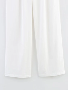 Detailed close-up of white wide-leg trousers showing smooth fabric texture and hem stitching