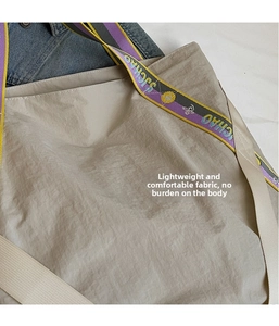 Détail d'un sac cabas beige en nylon froissé léger avec bandoulière en sangle colorée tissée