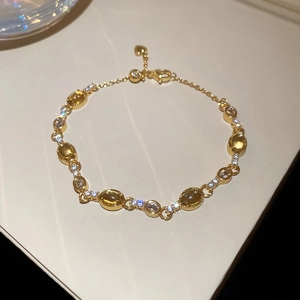 Detail of gold butterfly bracelet with yellow oval stones and heart charm tail chain