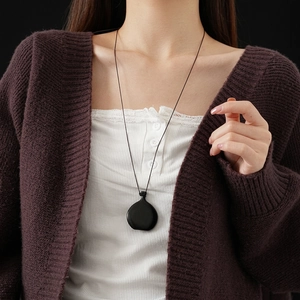 Minimalist black round pendant necklace on long cord, worn with brown knit sweater