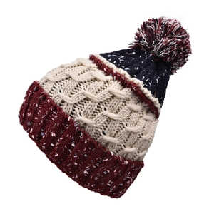 Détail du bonnet en maille tricolore avec texture torsadée et pompon en peluche