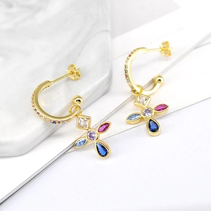Detailed macro view of C-shaped gold hoop earrings featuring multi-colored zircon flowers