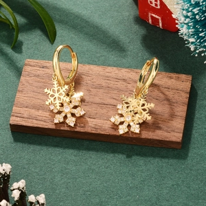 Detailed macro shot of festive gold snowflake earrings with diamond inlays on green felt