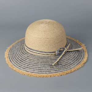 Detail of raffia straw hat with blue striped brim and rustic fringe trim bow decoration