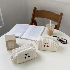Detailed close-up of quilted cotton cosmetic bags featuring delicate cherry embroidery