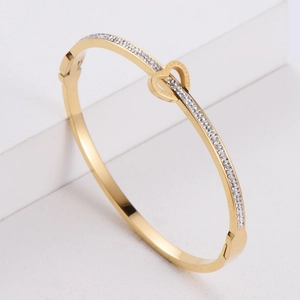 Polished gold stainless steel bangle with double heart buckle and pave set zircon stones