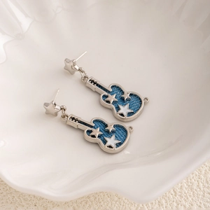 Macro shot of silver guitar earrings with blue denim fabric and star pattern details