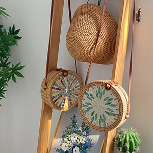 Handmade woven shell inlay crossbody bags with brown leather straps hanging on a wood ladder