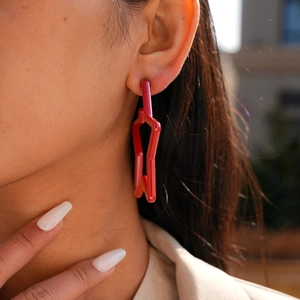 Close-up of model wearing vibrant red acrylic star-shaped stud earrings in natural light