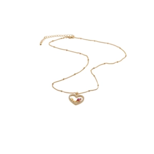 Détail d'un pendentif cœur doré avec une pierre rouge et l'inscription LOVE gravée