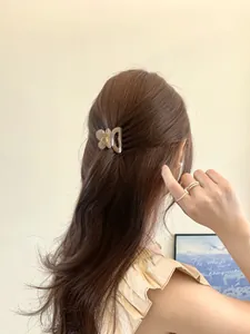 Détail d'une pince à cheveux papillon beige fixant une coiffure demi-attachée chic