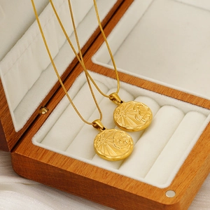 Detail of gold titanium zodiac coin pendant with embossed sun motif and snake chain