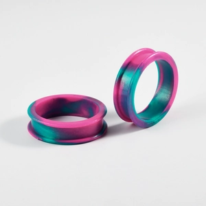 Detail view of pink and teal tie-dye silicone ear gauges for stretched ear piercings