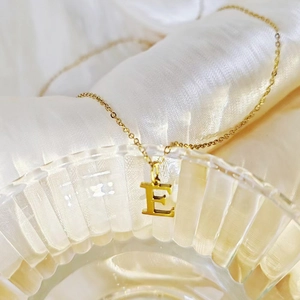 Detailed close-up of a golden capital letter E pendant necklace on a fine chain