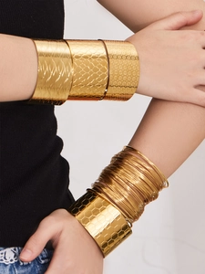 Gros plan de bracelets joncs plaqués or 18 carats aux textures nid d'abeille et fleurs