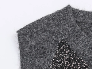 Macro detail of grey knit fabric with geometric black sequin rhombus pattern