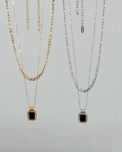 Detail of layered gold and silver Figaro chains with vintage black square pendants