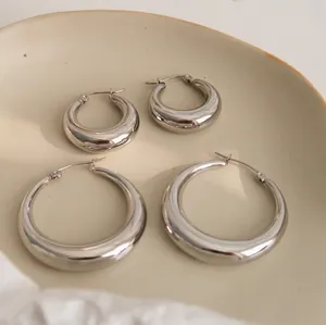 Minimalist thick silver oval hoop earrings in large and small sizes on ceramic plate
