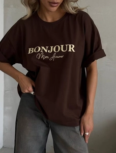 Detail eines dunkelbraunen Baumwoll-T-Shirts mit gelbem BONJOUR-Schriftzug auf der Brust