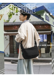 Outdoor shot of a black waterproof nylon messenger bag featuring a minimalist street style
