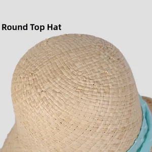 Detailed close-up of woven straw hat round top with blue dotted ribbon decoration