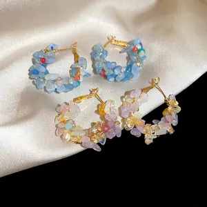 Golden hoop earrings with colorful natural crushed stones on soft white satin fabric