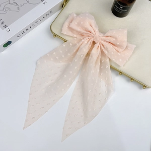 Close-up of light pink chiffon hair bow with white polka dot texture on a tray