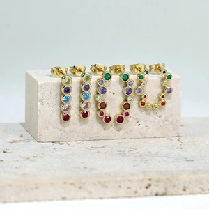 Detailed macro shot of gold plated stud earrings with multi-color faceted zirconia stones