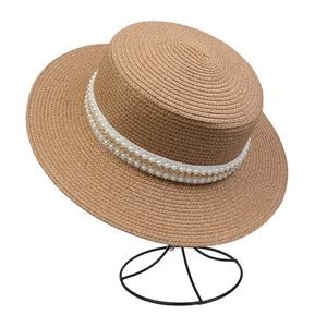 Detailed texture of straw sun hat with elegant pearl and golden metal chain decoration