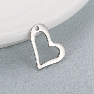 Sleek silver heart-shaped stainless steel pendant charm on a white ceramic dish