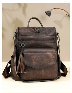 Detail of vintage brown leather backpack with tassel charm and multiple zipper pockets