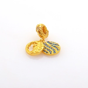 Detailed macro of gold charm pendant with blue stone inlay and floral engraving