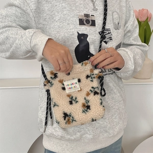 Detail of plush cream lamb wool bag with colorful floral patterns and adjustable cord strap