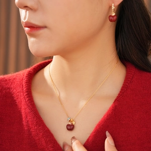 Dettaglio di set collana e orecchini placcati oro 18k con ciondoli a mela rossa e zirconi